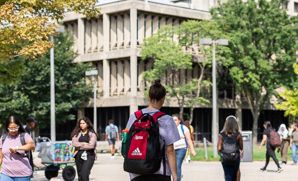 Student walking on campus with red backpack